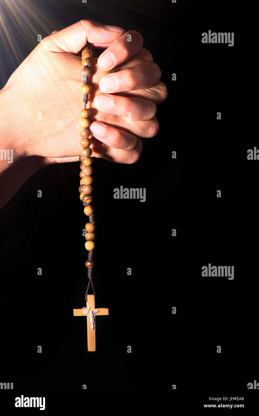 Rosenkranz-Krone in der Hand auf schwarzem Hintergrund. Stockfoto