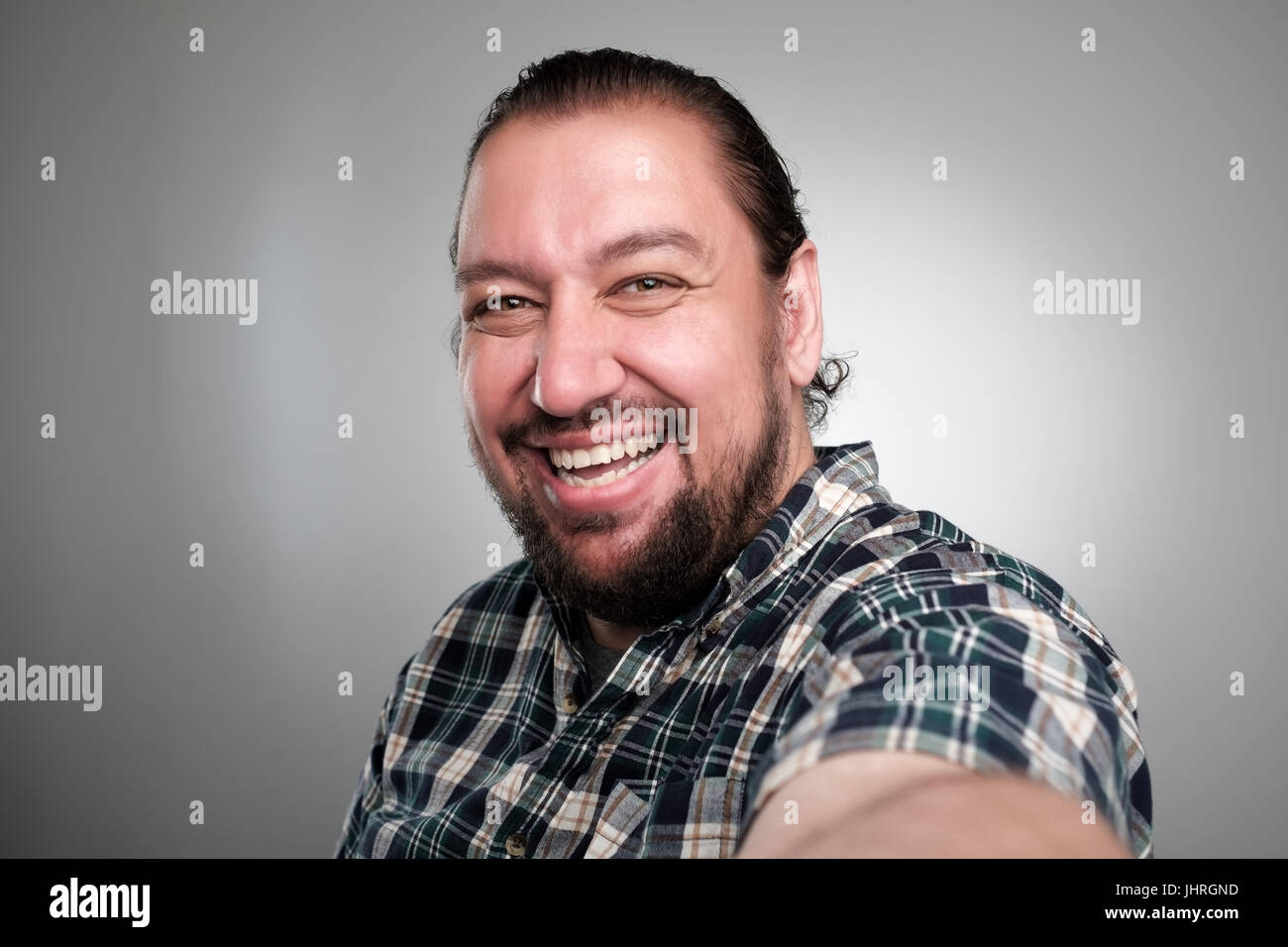 Schöner junger Mann in Freizeitkleidung machen Selfie auf grauem Hintergrund. Er hat ein glückliches Gesicht lächelnd mit Zähnen. Stockfoto