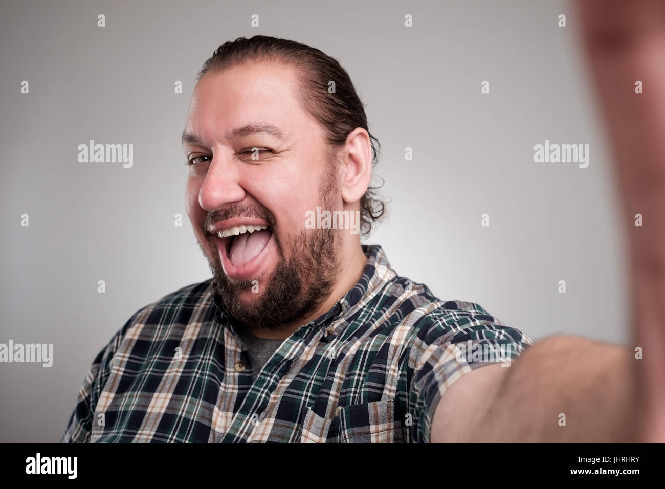 Schöner junger Mann in Freizeitkleidung machen Selfie auf grauem Hintergrund. Er hat ein glückliches Gesicht lächelnd mit Zähnen. Stockfoto