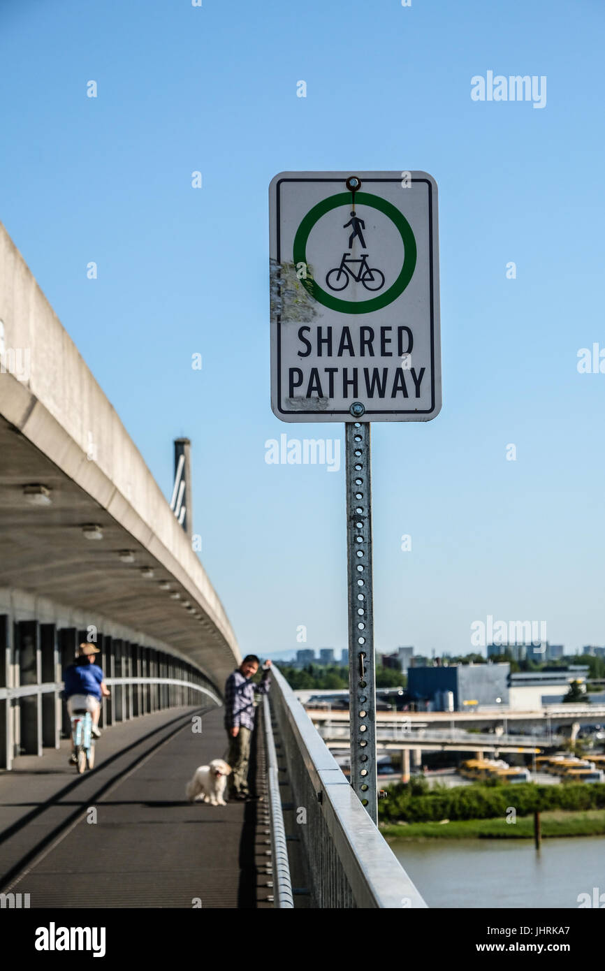 Eine gemeinsame Weg-Zeichen und ein Junge mit seinem Hund zu Fuß auf North Arm Canada Line Skytrain Brücke über den Fraser River zwischen Richmond und Vancouver Stockfoto