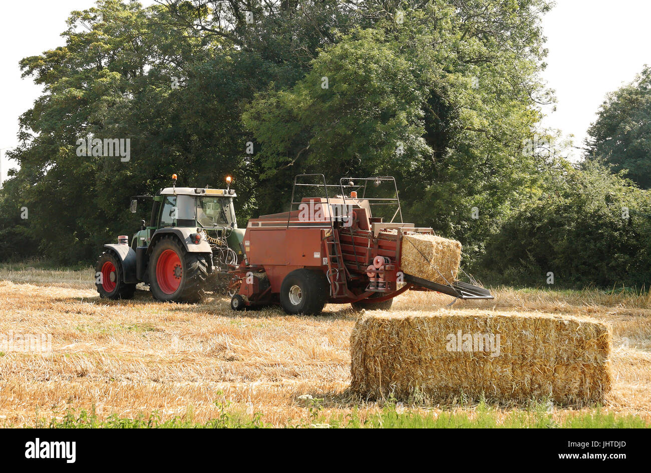 Traktor und Heu Pressen Maschine bei der Arbeit in einem englischen Feld Stockfoto