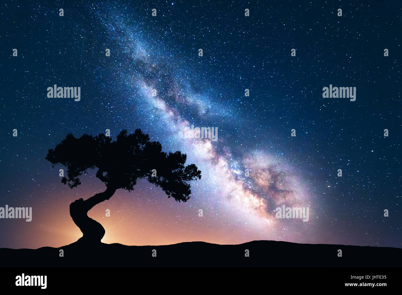 Milky Way mit allein alten krummen Baum auf dem Hügel. Bunte Nachtlandschaft mit hellen Milchstraße, Sternenhimmel und Baum im Sommer. Weltraum Hintergrund Stockfoto