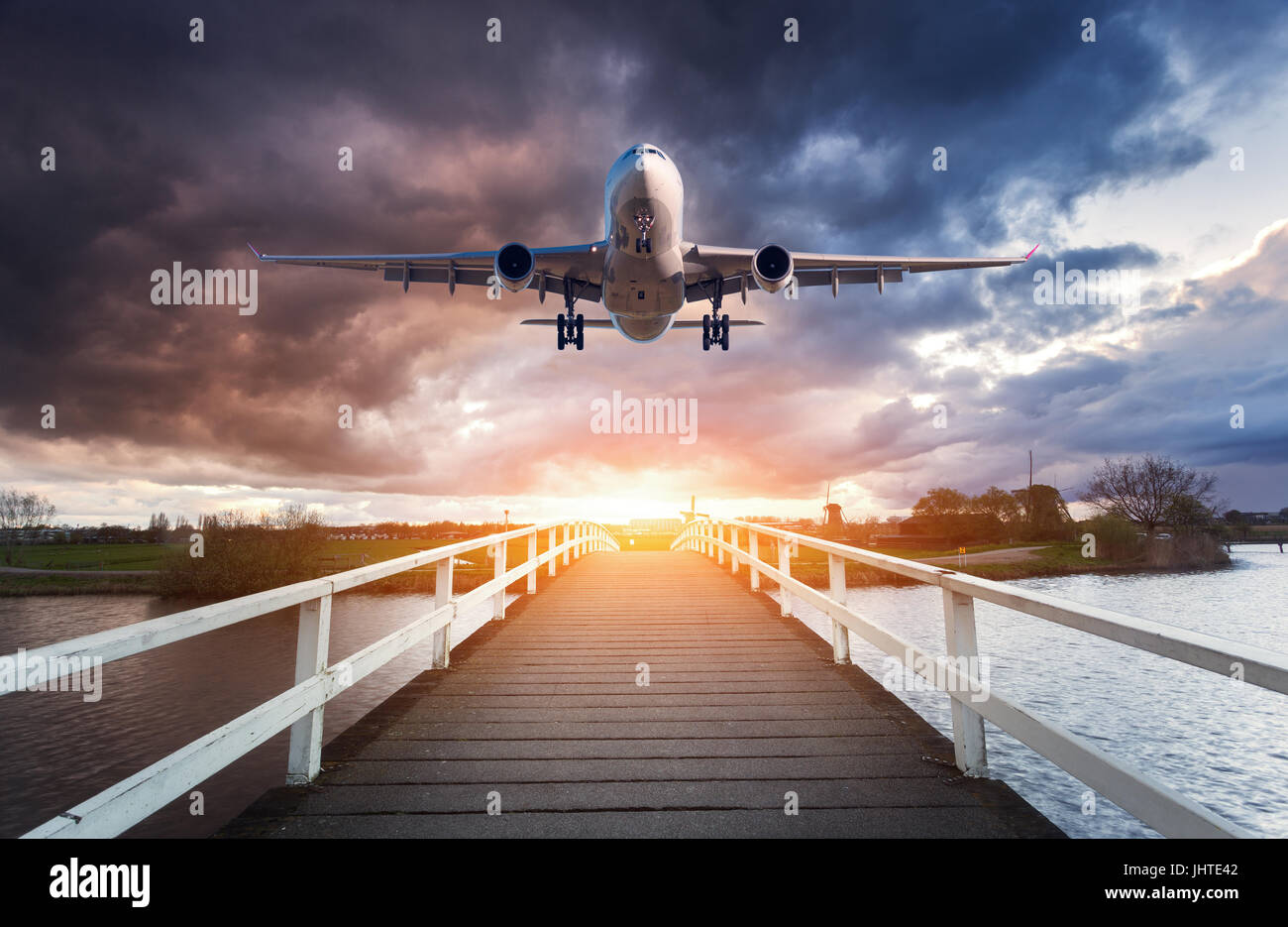 Flugzeug und Holzbrücke. Landschaft mit Passagierflugzeug fliegt über den Holzsteg gegen bedecktem Himmel bei Sonnenuntergang. Reise. Passagier-Luft Stockfoto