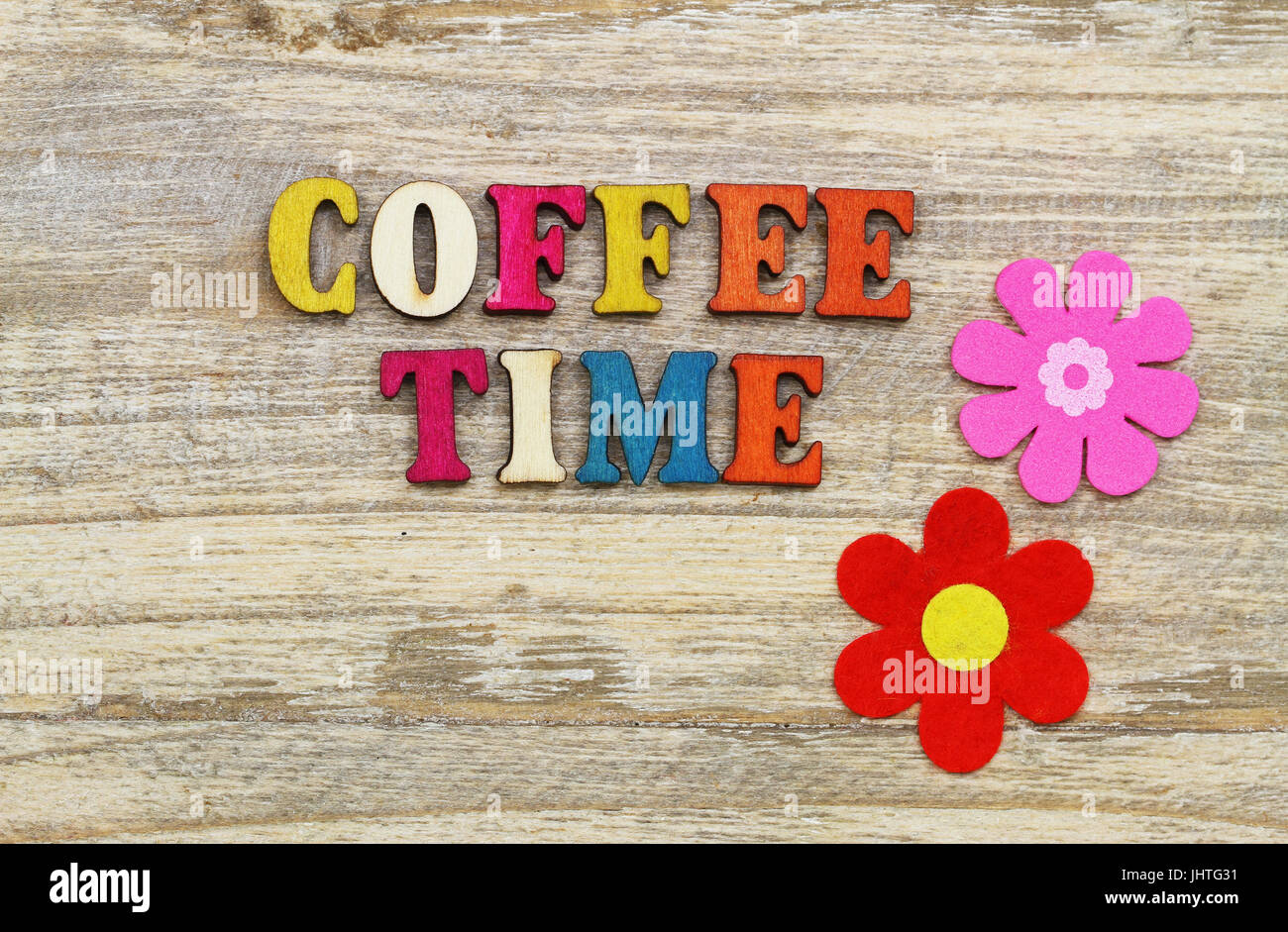 Kaffee-Zeit mit bunten Holzbuchstaben auf Holzoberfläche und zwei Blumen geschrieben Stockfoto
