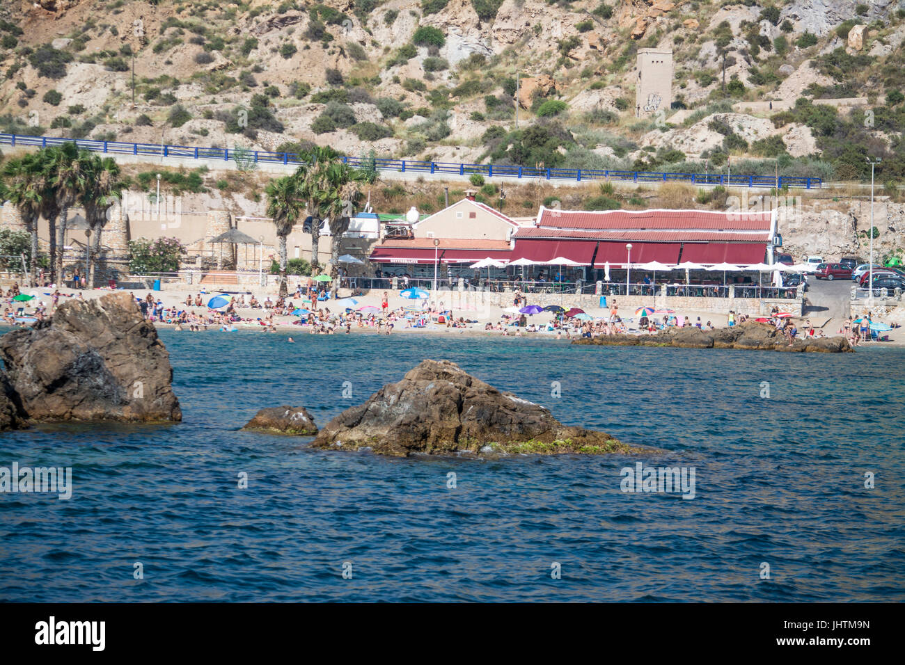 Sonnenanbeter am Strand vor dem Restaurant in Cala Cortina in der Nähe von Cartagena in Murcia Spanien Stockfoto