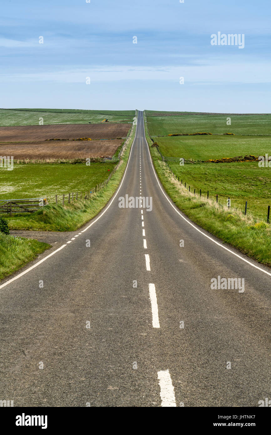 Lange gerade Asphaltstraße mit offenen Feldern, verschwinden über weitem Horizont, Insel der Orkney, Schottland, UK Stockfoto