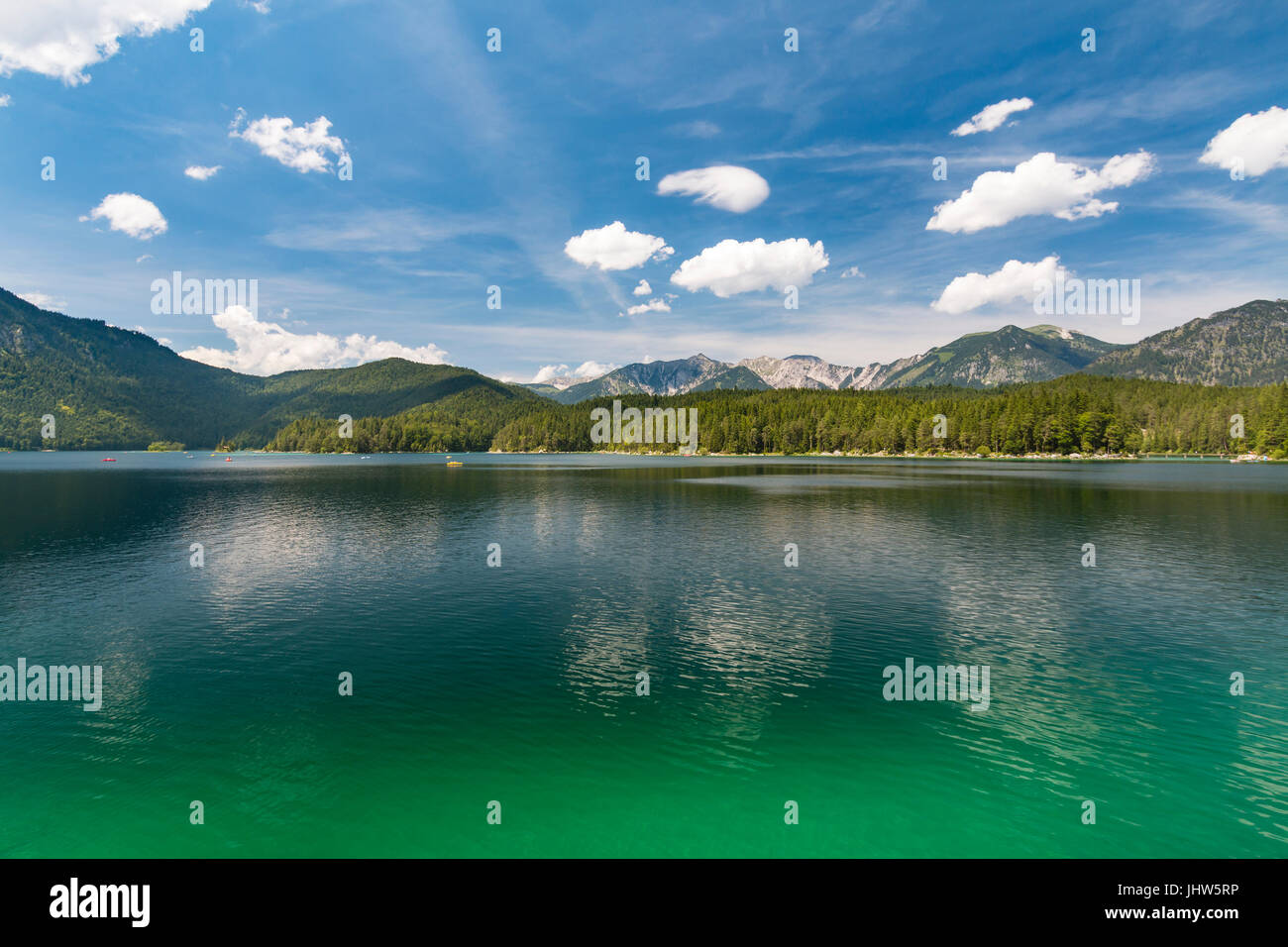 Blick über See Eibsee in Garmisch-Partenkirchen, Deutschland im Sommer zu einer fernen Bergkette mit blauem Himmel und grünen Wasser. Stockfoto