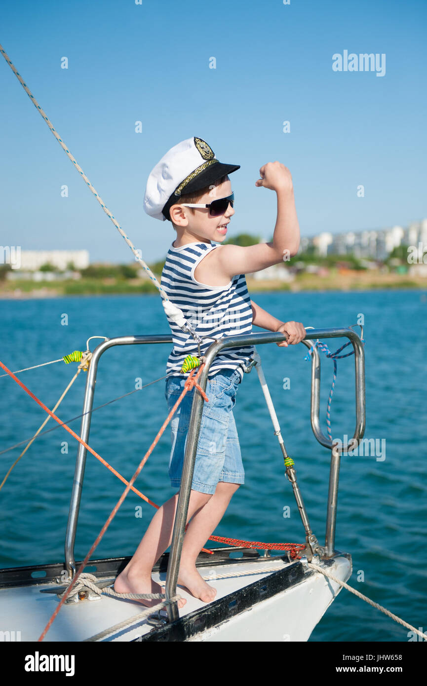 Starkes und gesundes Kind Kapitän zeigt Muskeln stehen an Bord der yacht Stockfoto