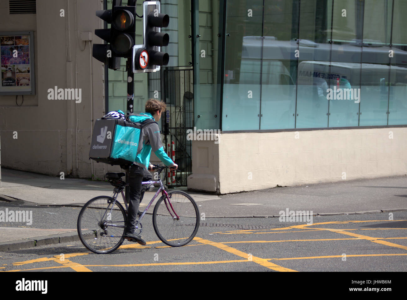 junger Mann Junge Lieferung Fahrrad Radfahrer Deliveroo Essen Lieferung SMS warten auf Arbeit liefern außerhalb Straße unterwegs Stockfoto