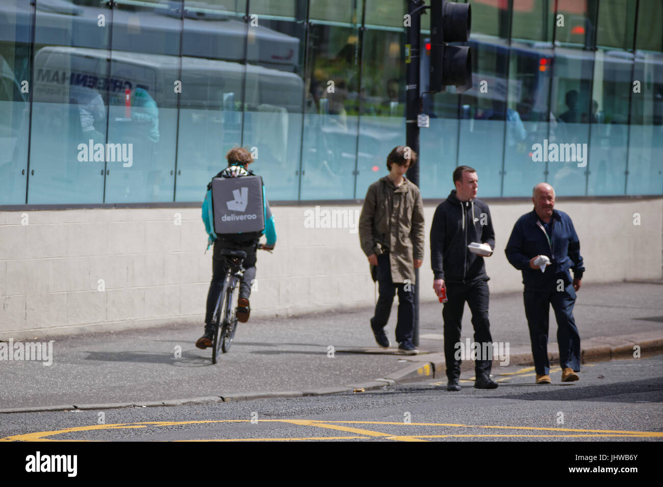 junger Mann Junge Lieferung Fahrrad Radfahrer Deliveroo Essen Lieferung SMS warten auf Arbeit liefern außerhalb Straße unterwegs Stockfoto