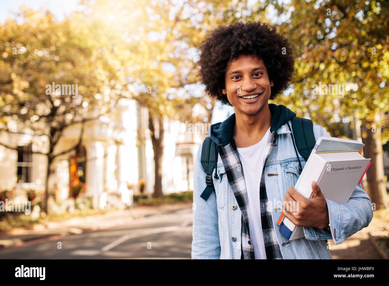 Junge Afro amerikanischen Studenten vom College zurück. Junge männliche Studenten mit Buch in College-Campus. Stockfoto