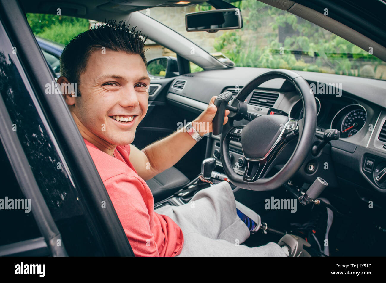 Tetraplegiker Mann sitzt im Sitz seines Autos individuelle Kontrolle. Er ist für die Kamera Lächeln. Stockfoto