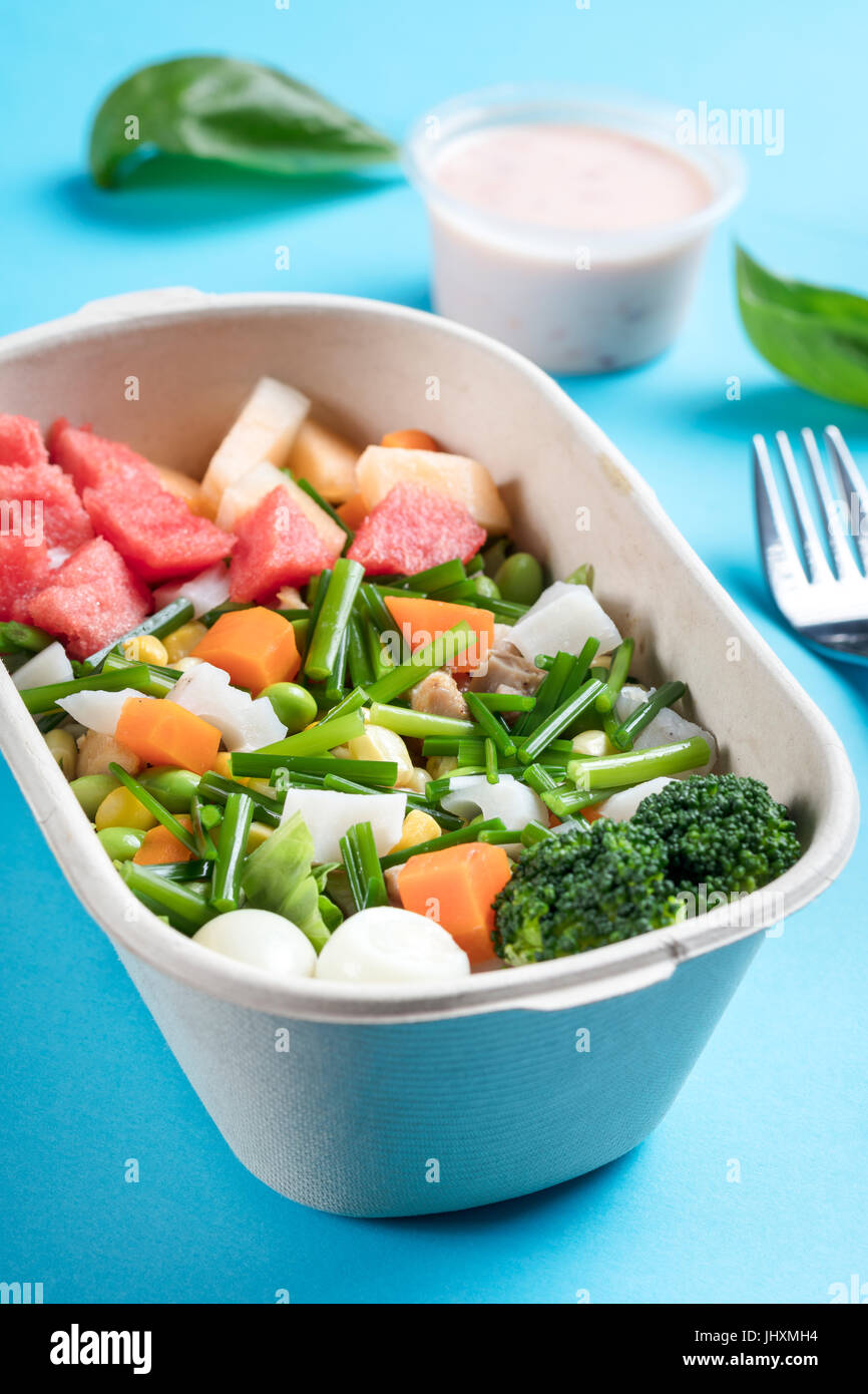 Eine Schüssel mit leckeren Chicken Salat auf dem blauen Hintergrund in einer To-Go-Box. Stockfoto