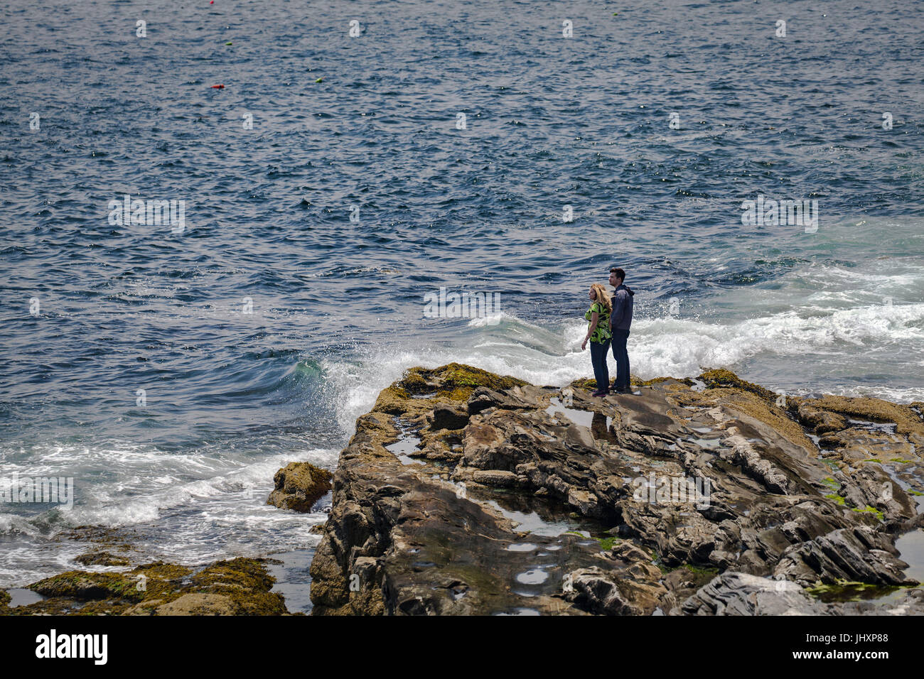 Ein junges Paar stand auf Welle getragen Felsen, Blick auf den Atlantischen Ozean in Bristol, Maine, USA. Stockfoto