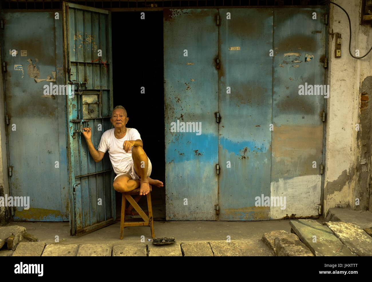 Ein ethnische chinesische Mann sitzt vor seinem Haus im Bereich Chinatown von Makassar, Süd-Sulawesi, Indonesien Stockfoto