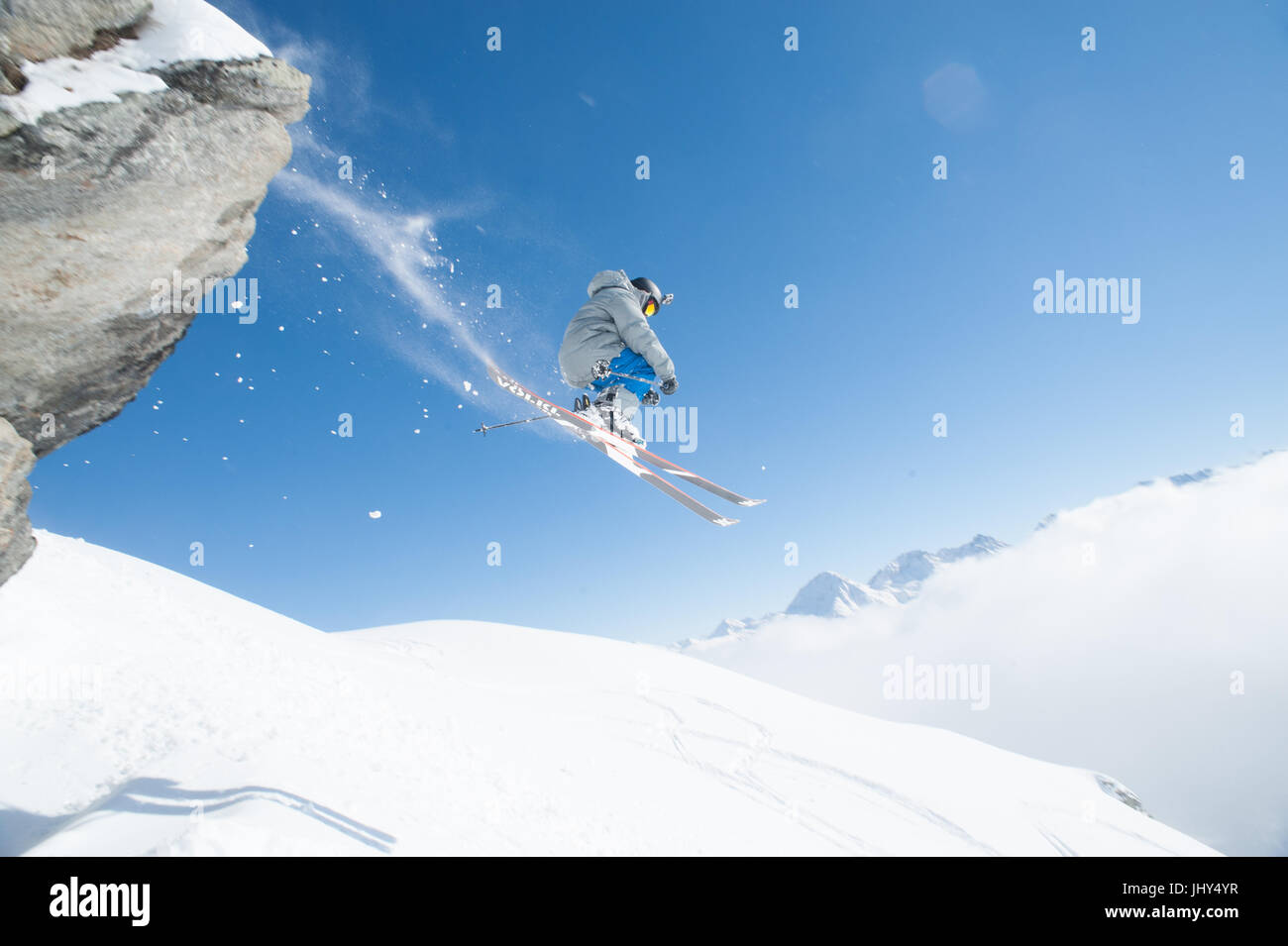 Skifahrer gehen über eine Klippe nachgestellte einen Spray von Schnee Stockfoto