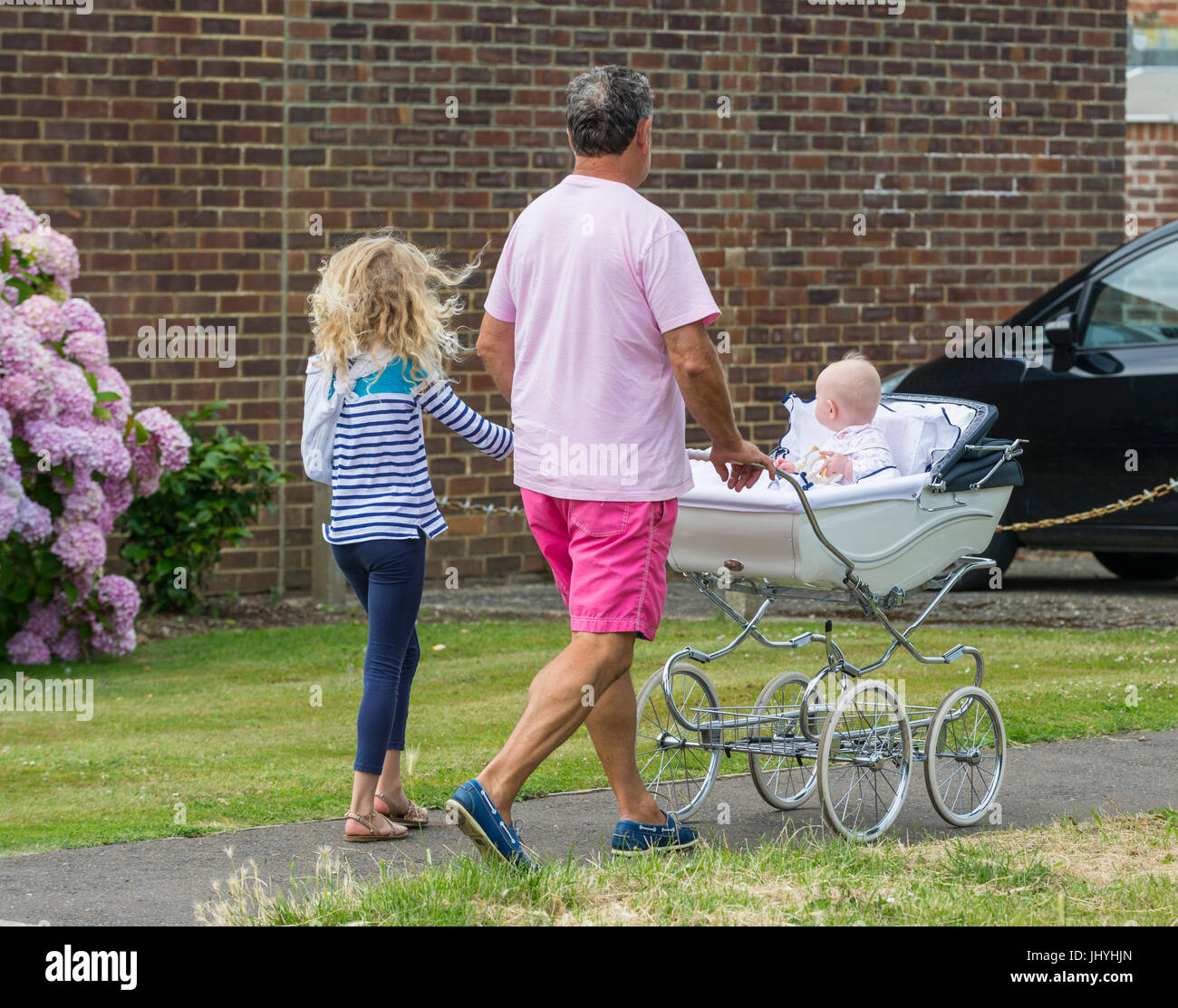 Mann mit einem Kind zu Fuß und schob einen Kinderwagen mit einem Baby. Single-Eltern-Familie. Stockfoto