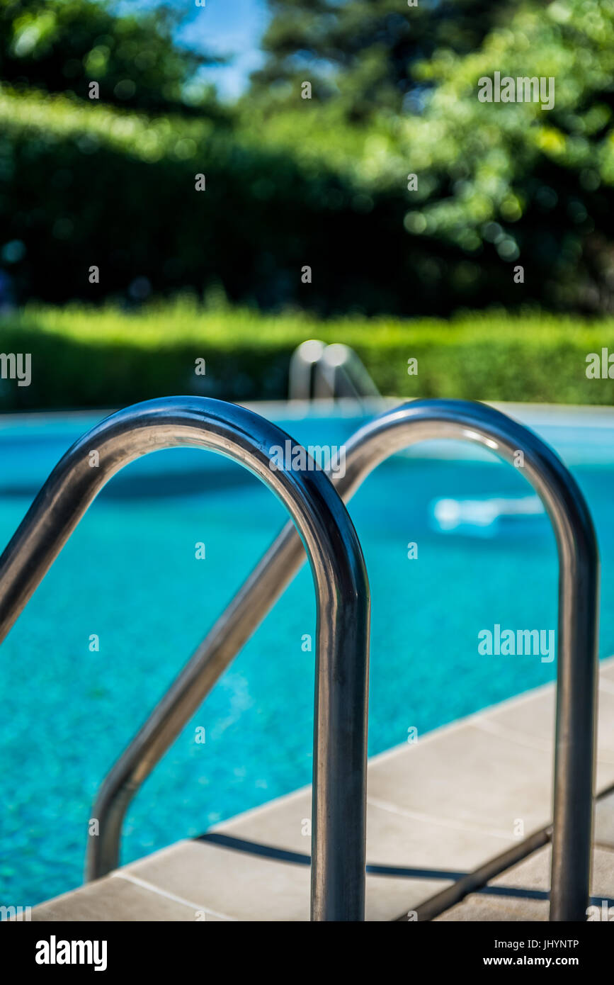 Schwimmbad Leiter schließen sich niemand im blauen Wasser und grünen Garten im Hintergrund unscharf Stockfoto