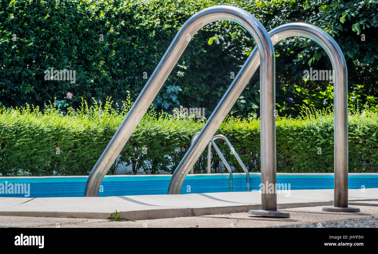 Schwimmbad Leiter schließen sich niemand im blauen Wasser und grünen Garten im Hintergrund unscharf Stockfoto