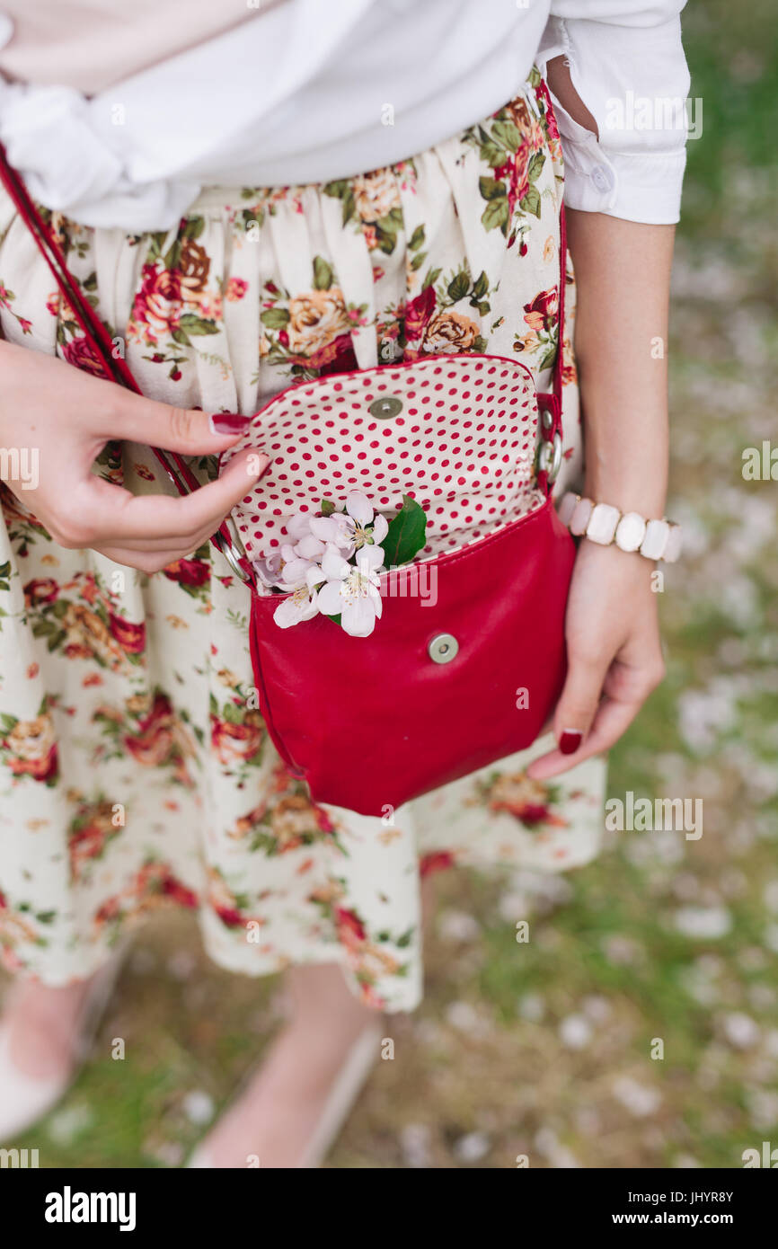 Elegantes Outfit. Nahaufnahme von roten gesteppte Leder Tasche Handtasche in Händen der stilvolle Frau. Modische Mädchen auf der Straße. Sonniger Tag. Weibliche Mode conce Stockfoto