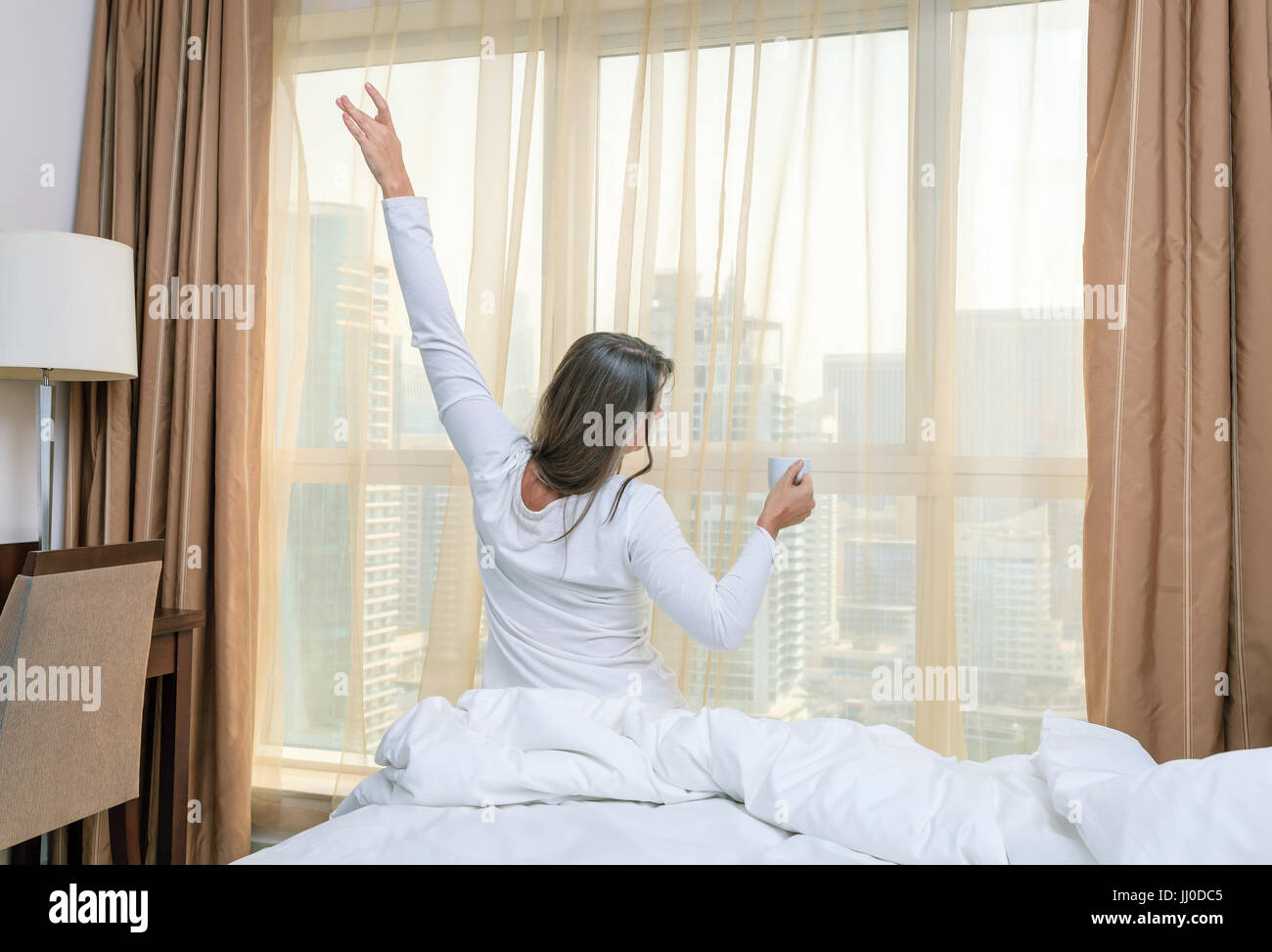 Reife Frau erwacht in ihrem Schlafzimmer in einem Hotel/apartment Stockfoto