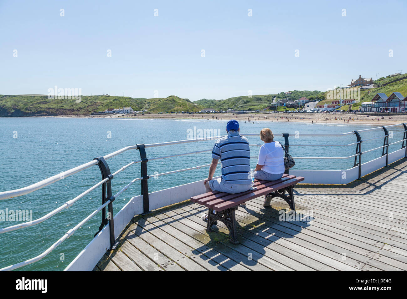 Ein Mann und eine Frau saß auf einer Bank auf dem Pier, Blick auf das Meer bei Saltburn am Meer, England, UK Stockfoto