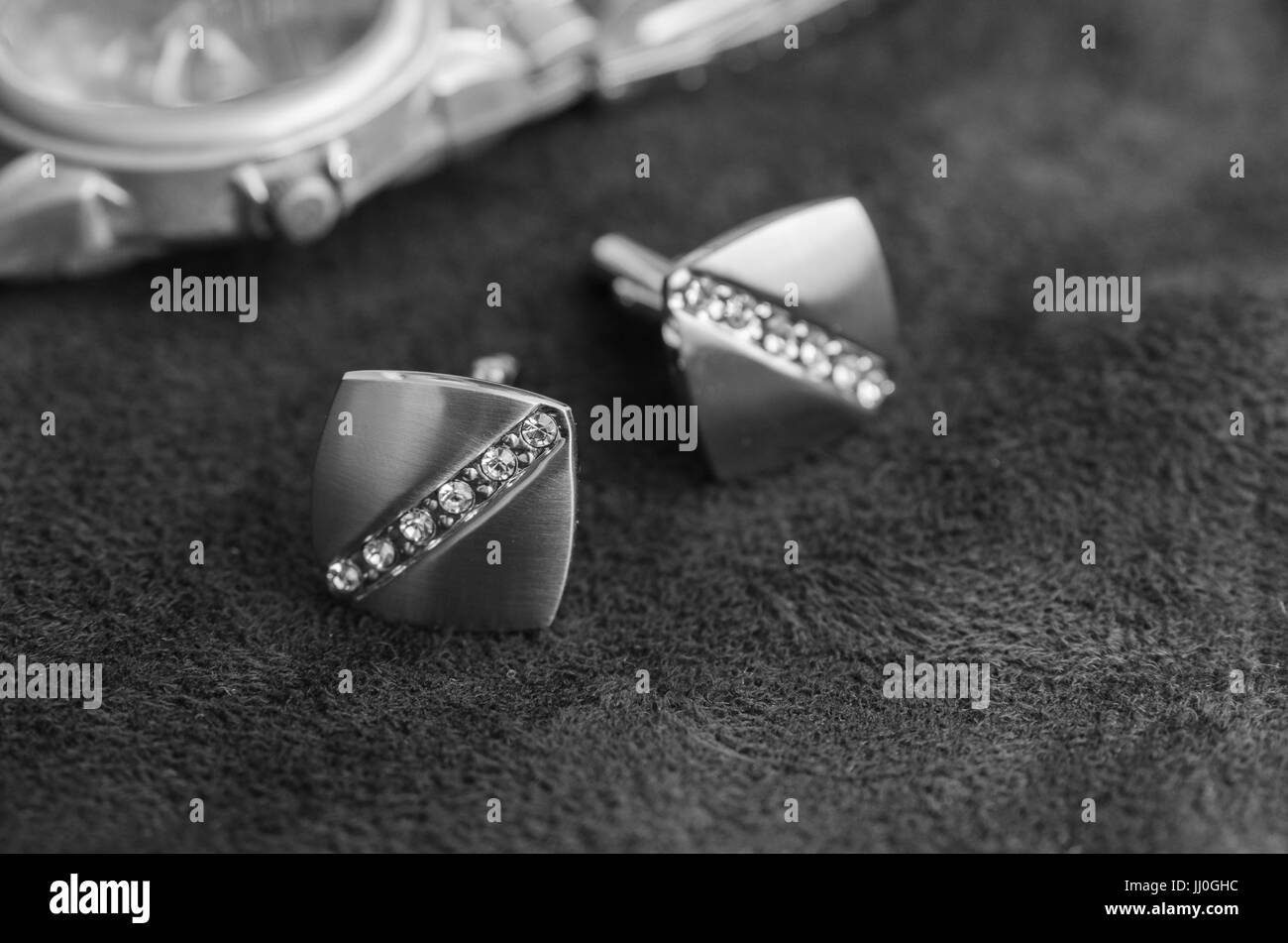 Silber Manschettenknöpfe mit Strass auf der dunklen Materie in der Nähe von Uhren, schwarz / weiß-Foto Stockfoto