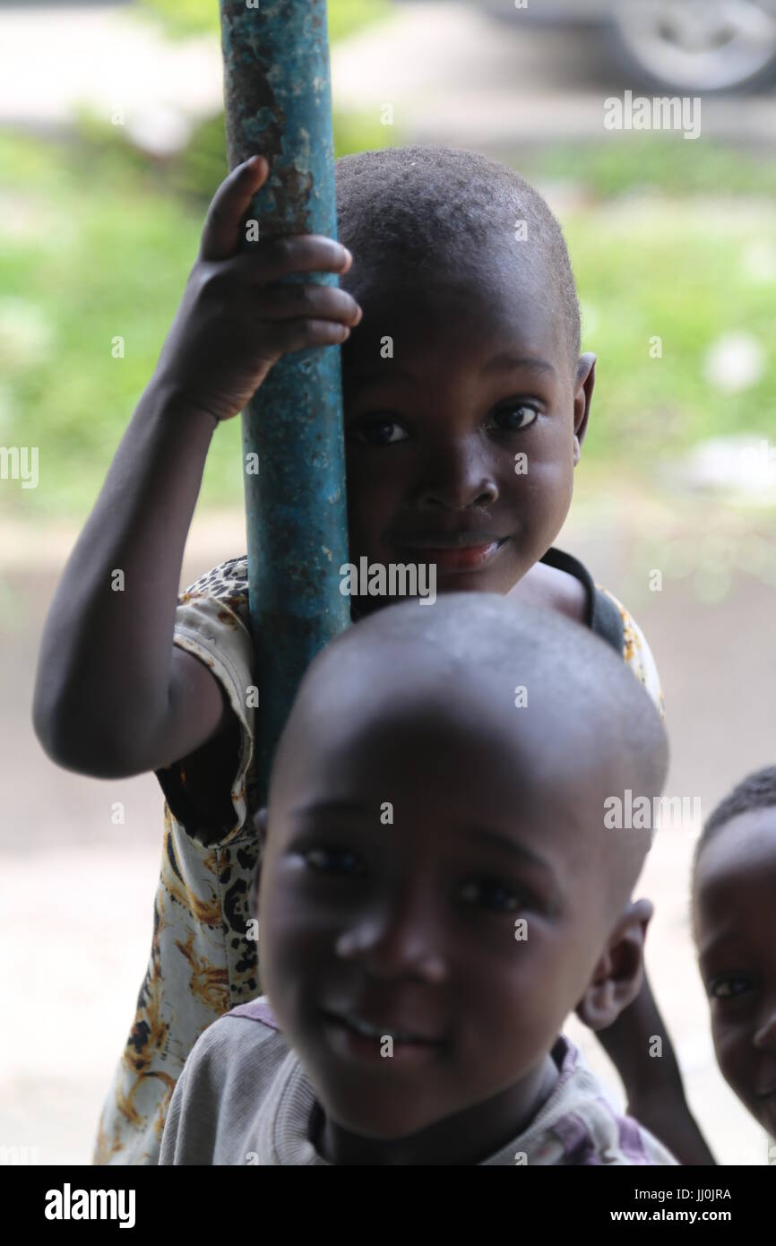 Kind hängt sich bei der öffentlichen Restaurant erwartet Essen und die Unterstützung der Kunden bei der öffentlichen Platz in capiltal Ivory-Coast in Abidjan Stockfoto