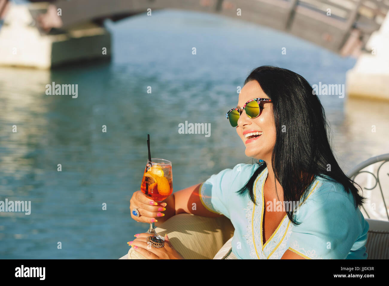 Glücklich schöne Bräunung Frau sitzen und trinken cocktail im Seaside Café, selektiven Fokus Stockfoto