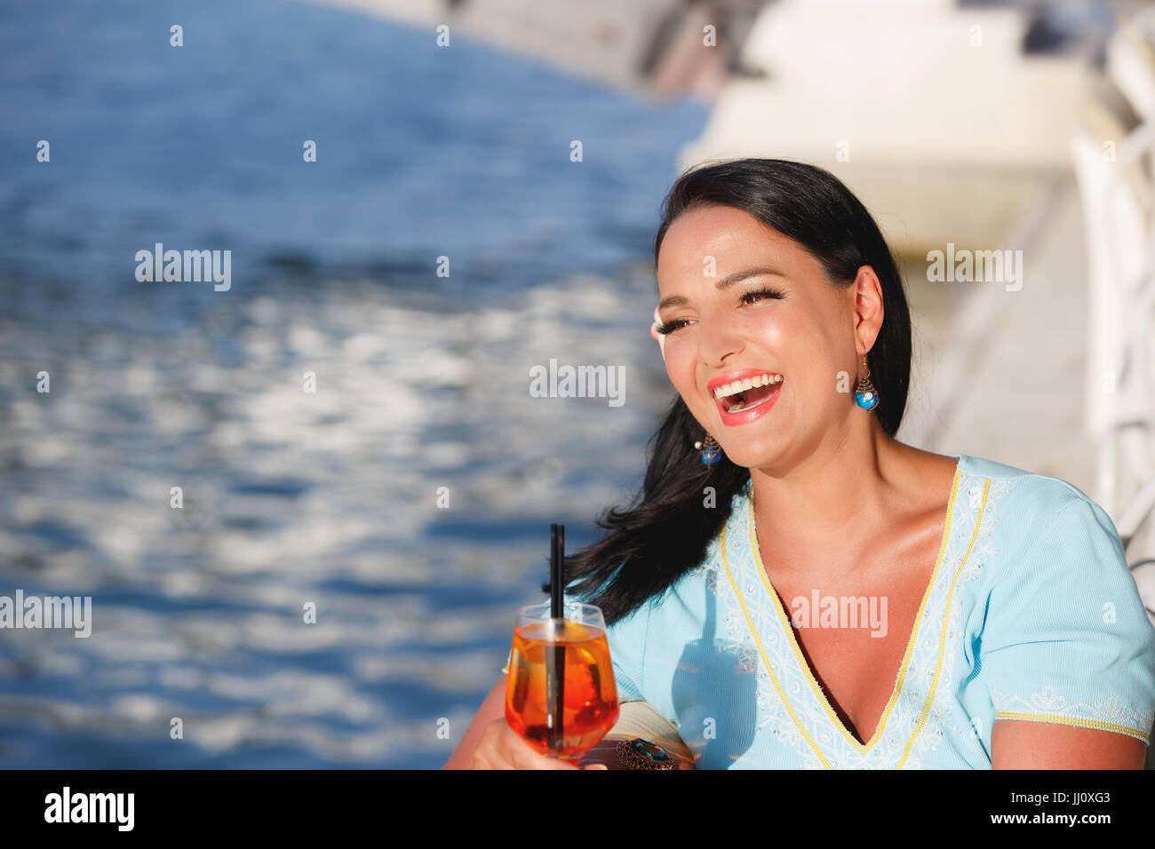 Glücklich schöne Bräunung Frau sitzen und trinken cocktail im Seaside Café, selektiven Fokus Stockfoto