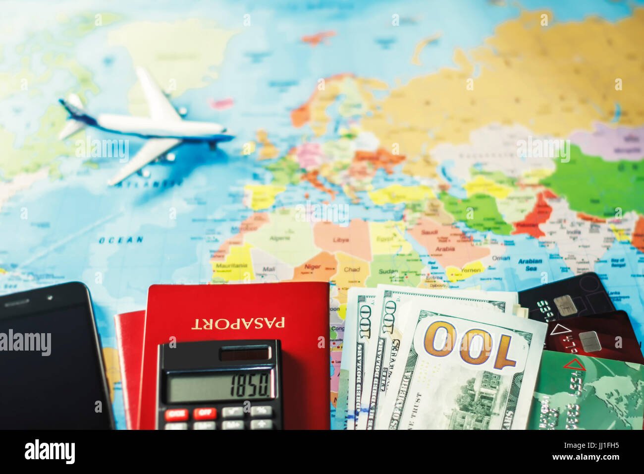 Reiseplanung mit US-Dollar-Banknoten, Taschenrechner, Smartphone und Flugzeug auf Weltkarte – Finanz-, Budget- und Tourismuskonzept. Stockfoto