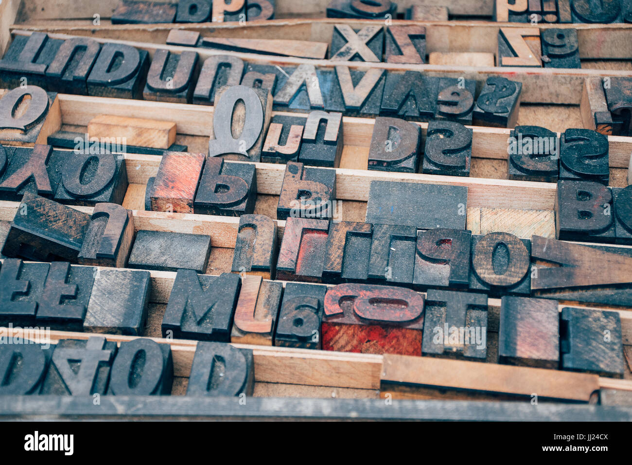 Vintage Schriftsatz Holzbuchstaben in einem Drucker-Tablett auf einem Flohmarkt mit Tinte in einem abstrakten Brief Muster Stockfoto