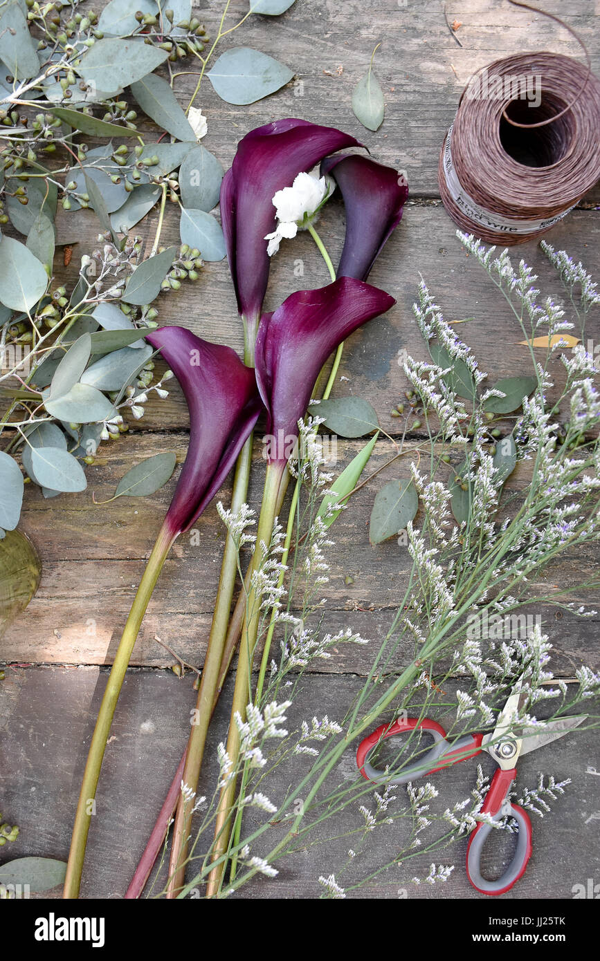 Hochzeit Blumen setup auf eine Holzbank im Sonnenlicht mit Schere, Garn, Eukalyptus und Lilien Stockfoto