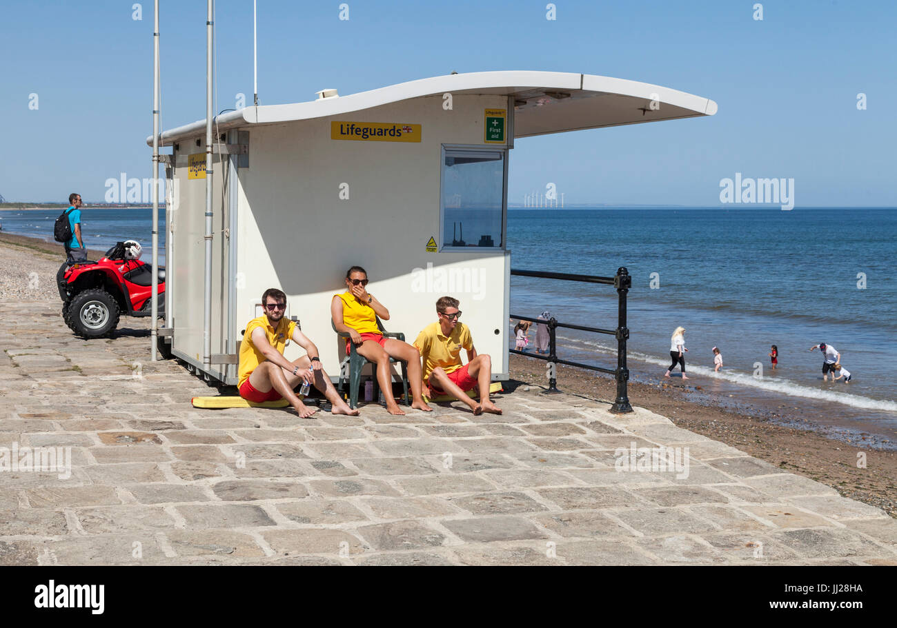 Drei Bademeister saß außerhalb ihrer Station, Blick auf das Meer bei Saltburn am Meer, England, UK Stockfoto