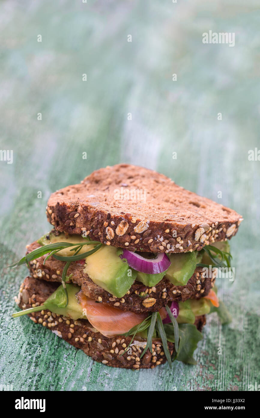 Countrybread Avocado, gesalzener Lachs Sandwich mit frischen Herss auf grünen craked Paintt Holzbrett Hintergrund. Gesunde Ernährung-Thema Stockfoto