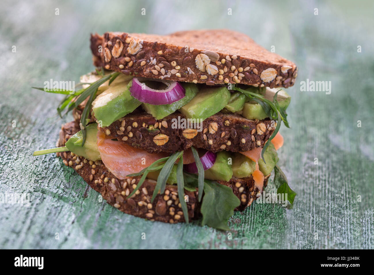 Countrybread Avocado, gesalzener Lachs Sandwich mit frischen Herden auf grüne craked Paintt Holzbrett Hintergrund. Gesunde Ernährung-Thema Stockfoto