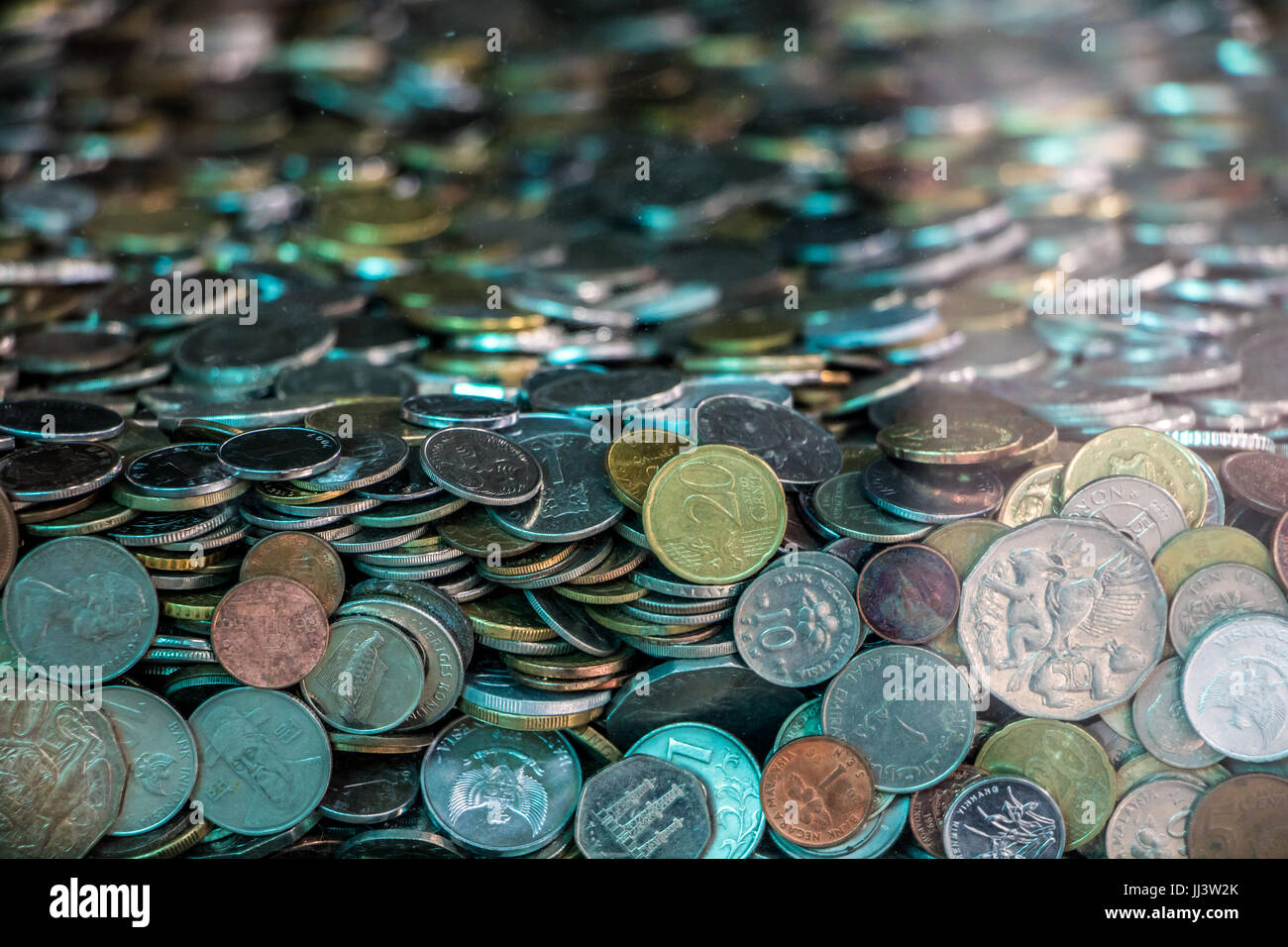 viele Münzen aus verschiedenen Ländern in Glasbox Stockfoto
