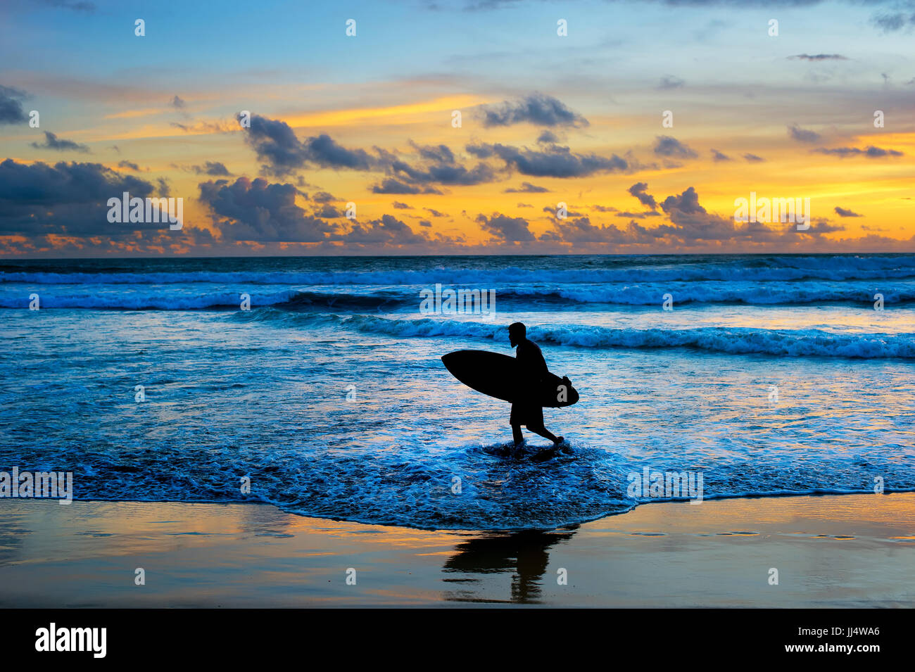 Hipster-Surfer mit Surfbrett bei Sonnenuntergang am Strand. Insel Bali Stockfoto