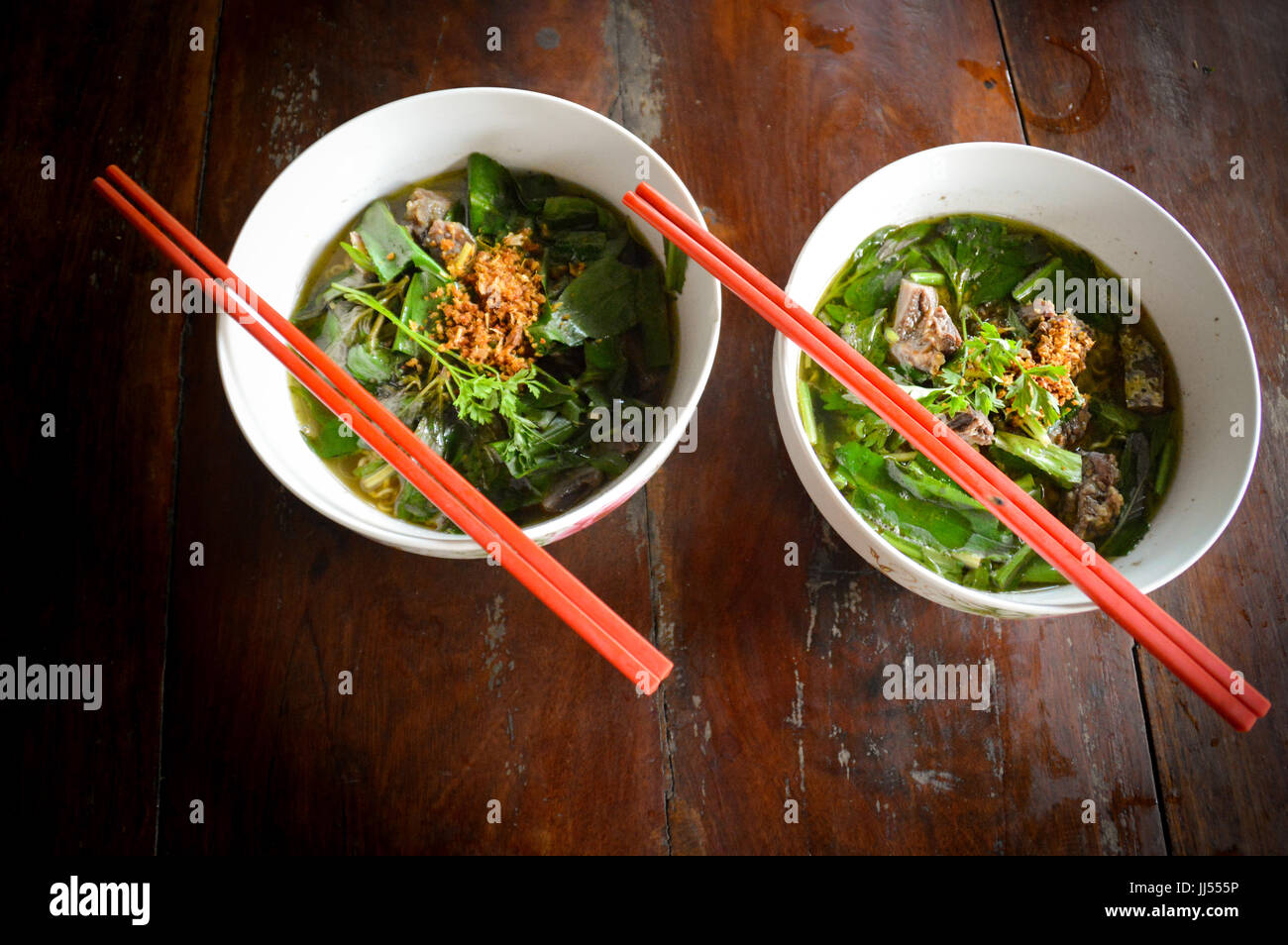 Zwei Schüsseln mit heißer Suppe und roten Stäbchen Stockfoto