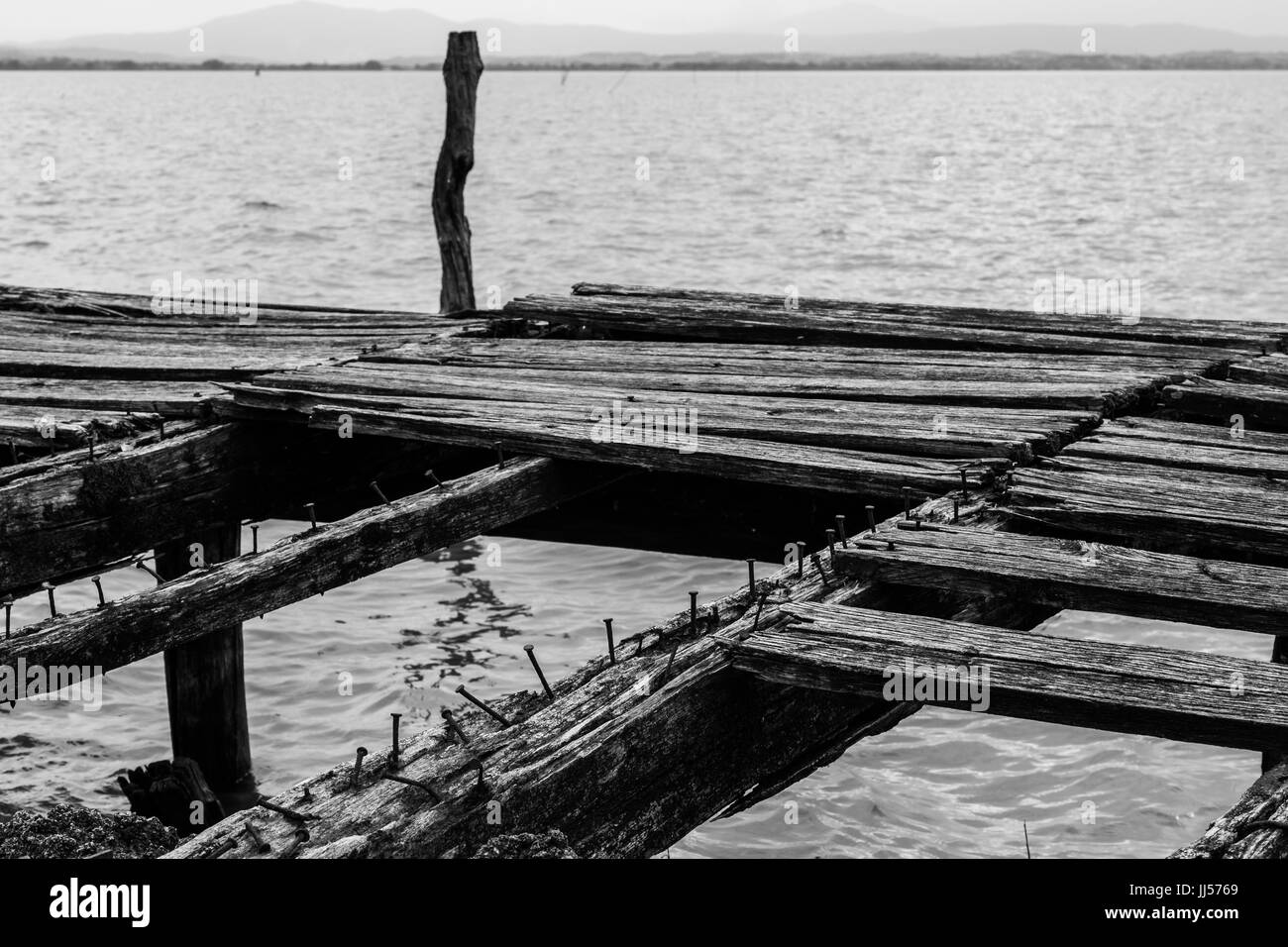 Details zu einer alten, gebrochenen Pier an einem See, mit Nägeln und abgenutzt und fehlende Holzplatten Stockfoto