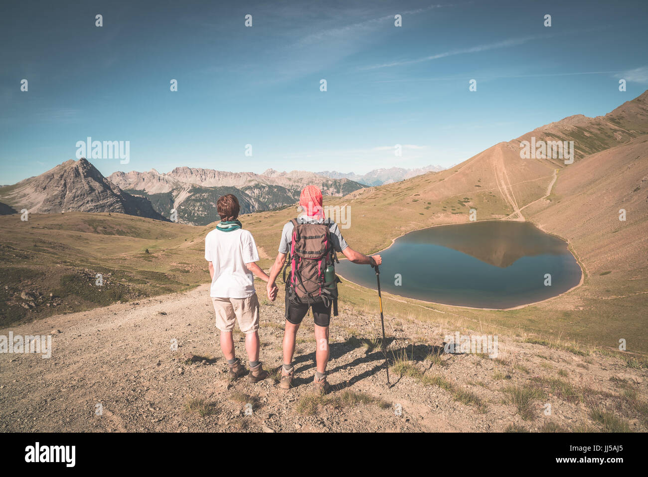 Paar der Wanderer auf den Berg Top Blick auf blaue See und die Berge Gipfel. Sommer Abenteuer in den Alpen. Weitwinkel-Ansicht von oben, getönten Bild V Stockfoto