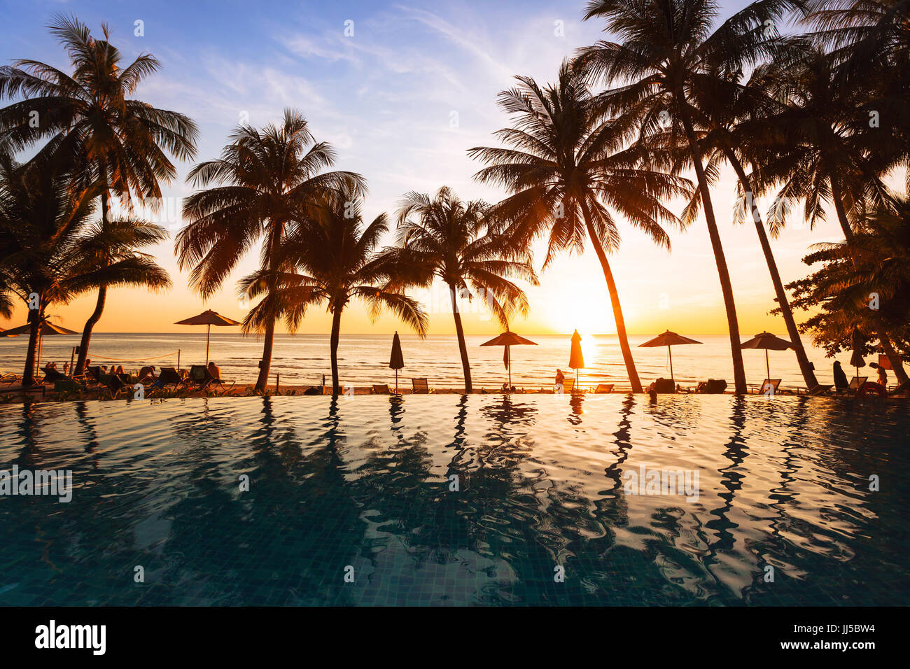Sonnenuntergang am Strand, Urlaub Hintergrund, Reflexion von Silhouetten von Palmen im Swimmingpool des Hotels Stockfoto