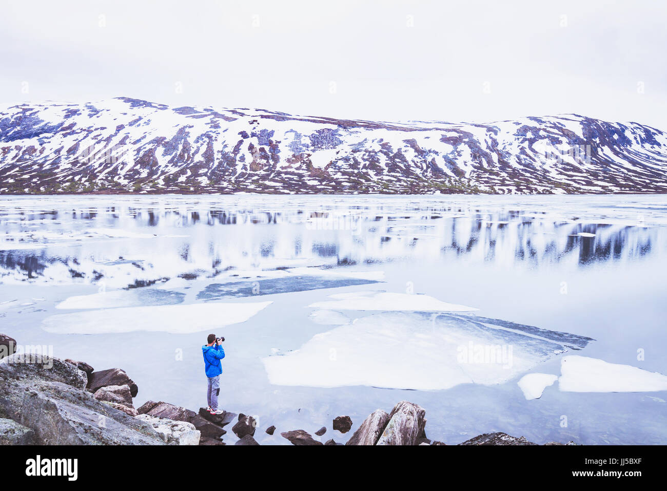 Reisen, Fotograf, Foto, verschneite Landschaft in Norwegen im Frühjahr, eine Person in der Nähe von wunderschönen zugefrorenen See, in den Bergen Stockfoto