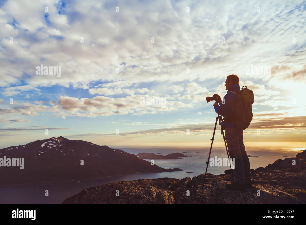 Fotograf mit Stativ-Aufnahme Panorama der wunderschönen Naturlandschaft in Norwegen bei Sonnenuntergang, Silhouette des Mannes mit Kamera in Fjorden Stockfoto