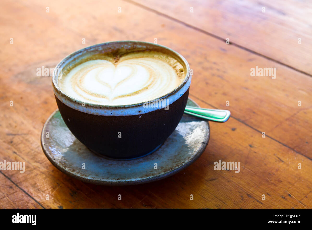 Schöne Tasse Kaffee Cappuccino auf hölzernen Tisch im Cafe Stockfoto