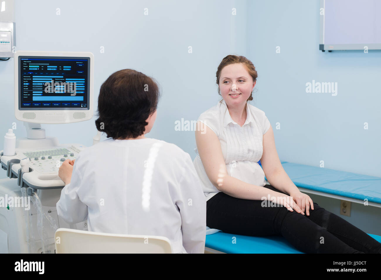 Zufrieden schwangere Frau, die ärztliche Visite mit Ultraschalldiagnostik. Stockfoto