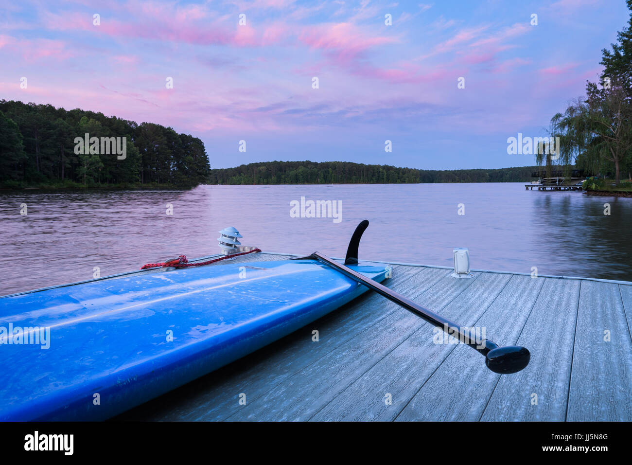 Blaues Paddel Board unter einem rosa Sonnenuntergang. Stockfoto