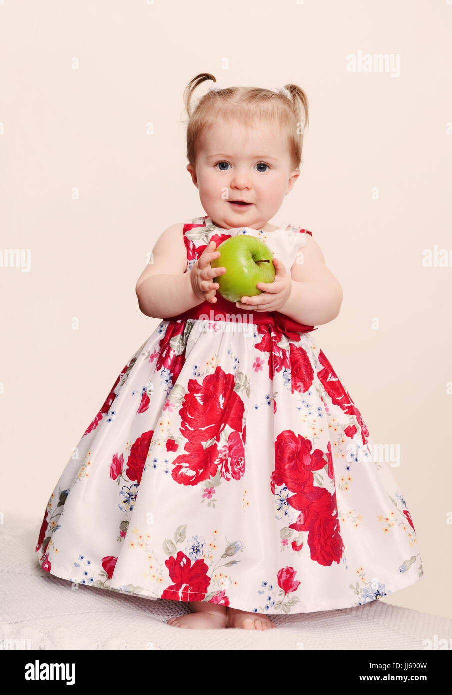 Schönes Baby Mädchen mit grünem Apfel auf einem hellen Hintergrund. retro Toning Stockfoto
