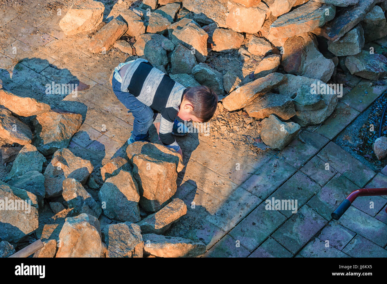 Kleiner Junge werfen einen Stein in ein Wasserfass Stockfoto