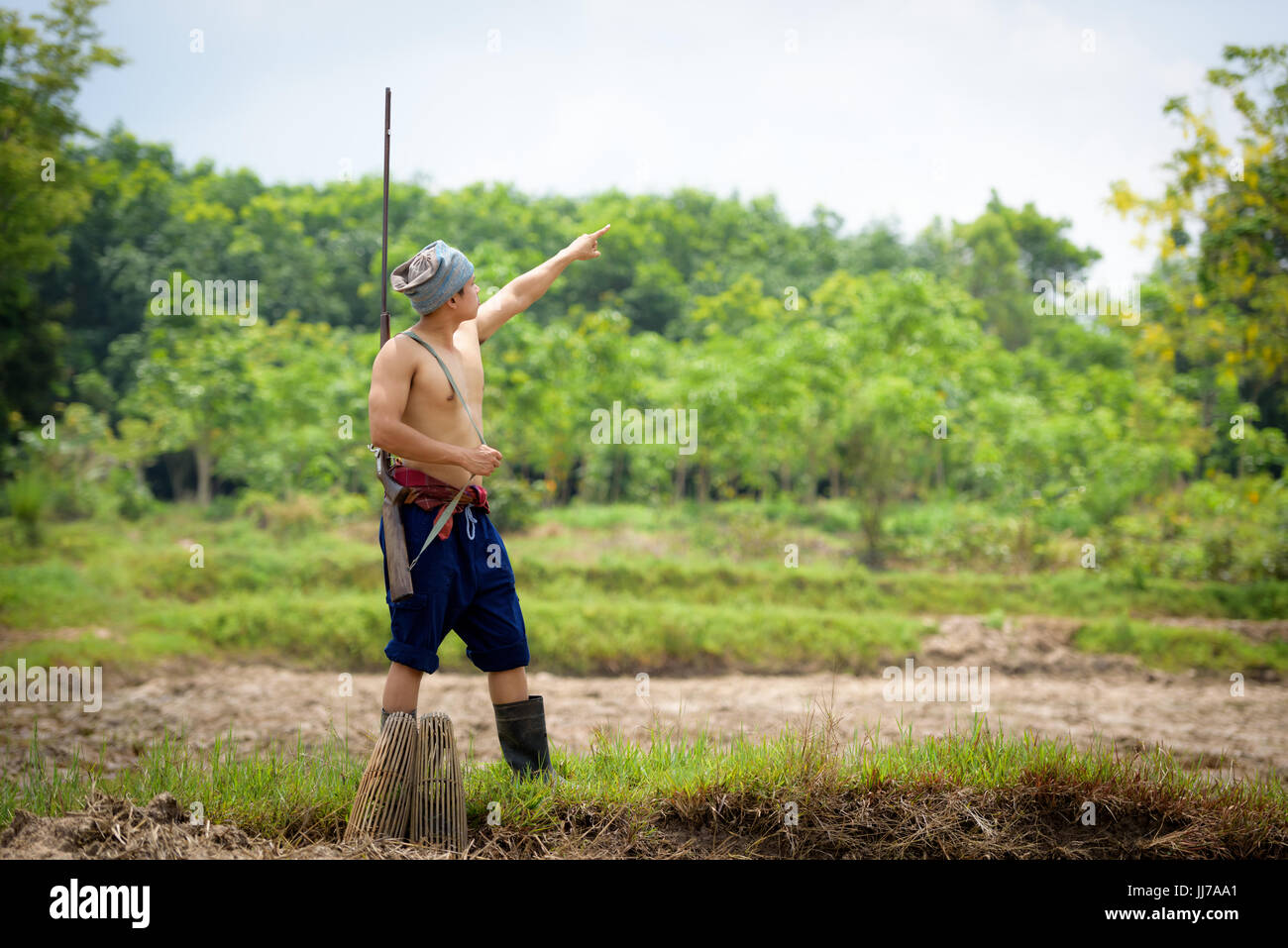 Männliche Landwirt trägt eine Gewehr Spaziergänge entlang und auf den Himmel Stockfoto